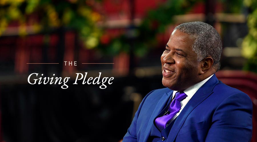 Robert F. Smith wears a blue suit and sits so that we see his profile