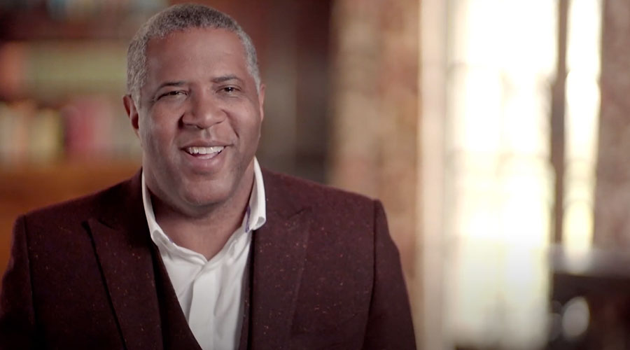 Robert F. Smith smiles facing the photographer wearing a white shirt with an open collar and a tweed suit jacket