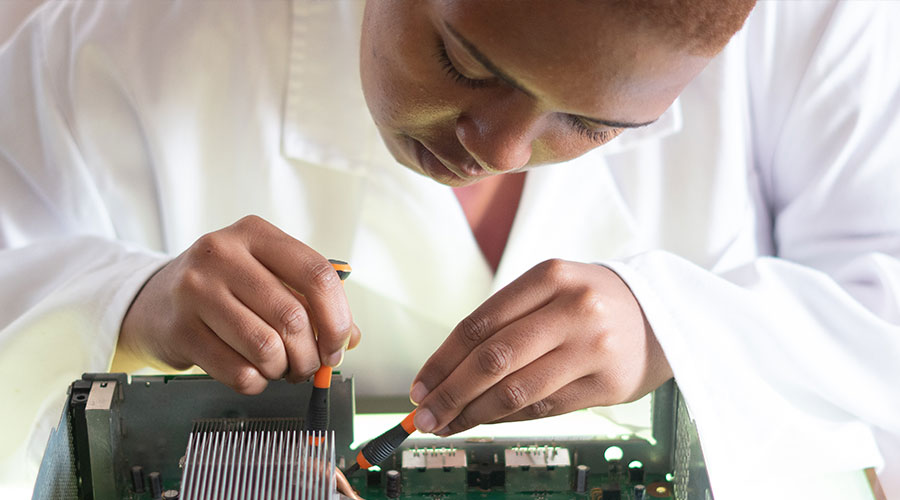African American wearing a lab coat works on a circuit board