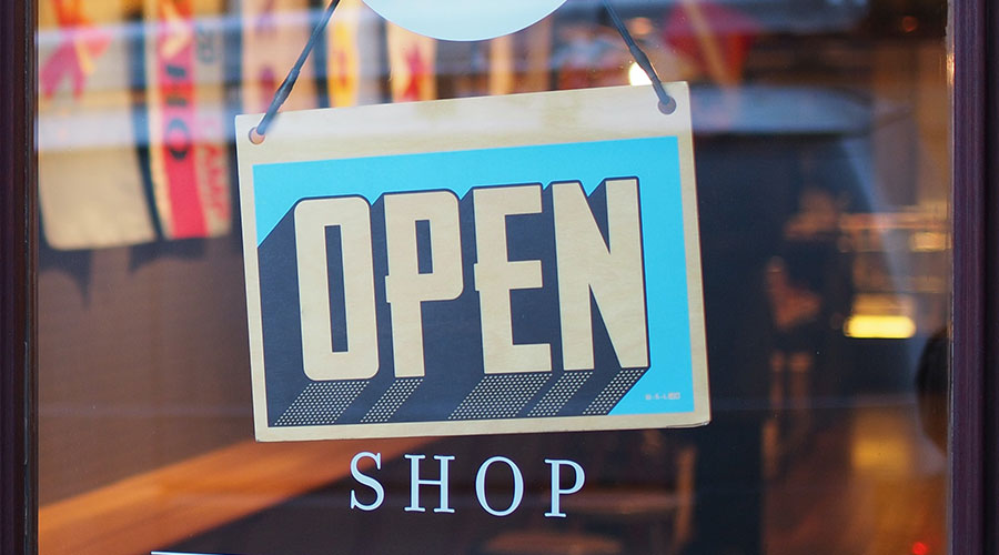 An OPEN sign is turned to face outward on a glass storefront door.