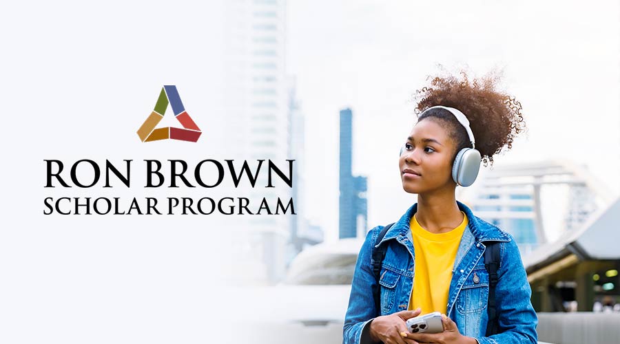 A Black woman stands outside with headphones on and an iPhone in her hand, with a graphic of the “Ron Brown Scholar Program” to the left of the woman