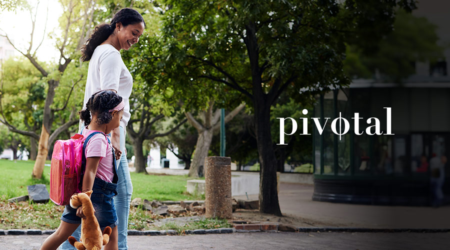 Mom and young daughter walk hand-in-hand in a park with the Pivotal Ventures logo on the right side of the image