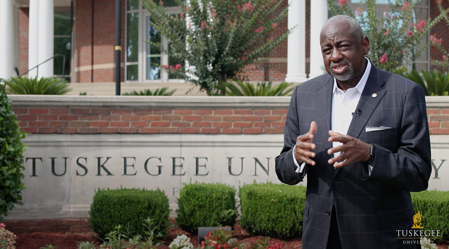 Dr. Mark A. Brown, standing in front of the Tuskegee University campus sign and speaking to the camera