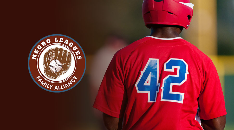 Youth baseball player, wearing a red jersey with the number 42 next to the Negro Leagues Family Alliance logo