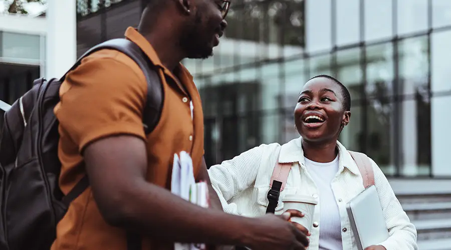 Two Black students walking outside and speaking to each other on a college campus