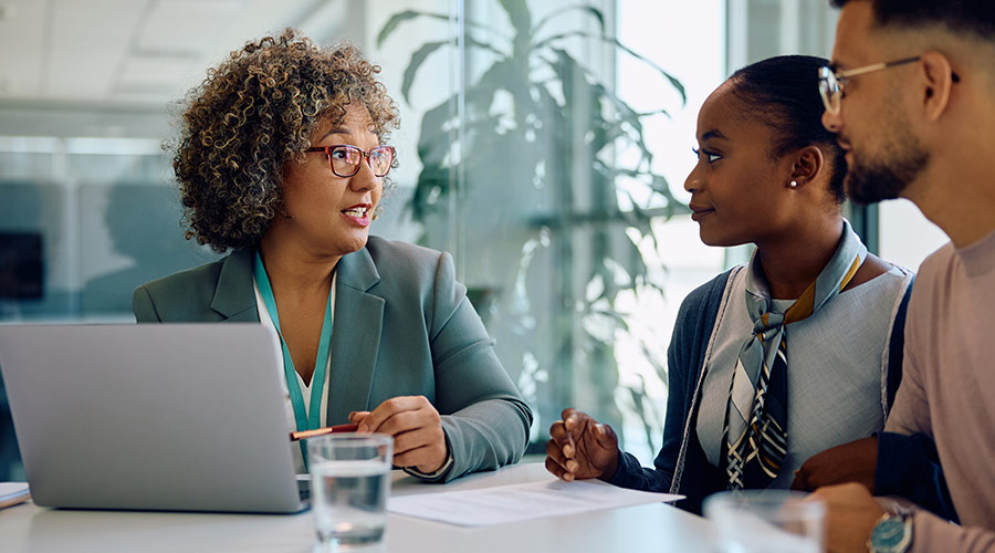 A Black female banker speaking to a young Black couple in an office