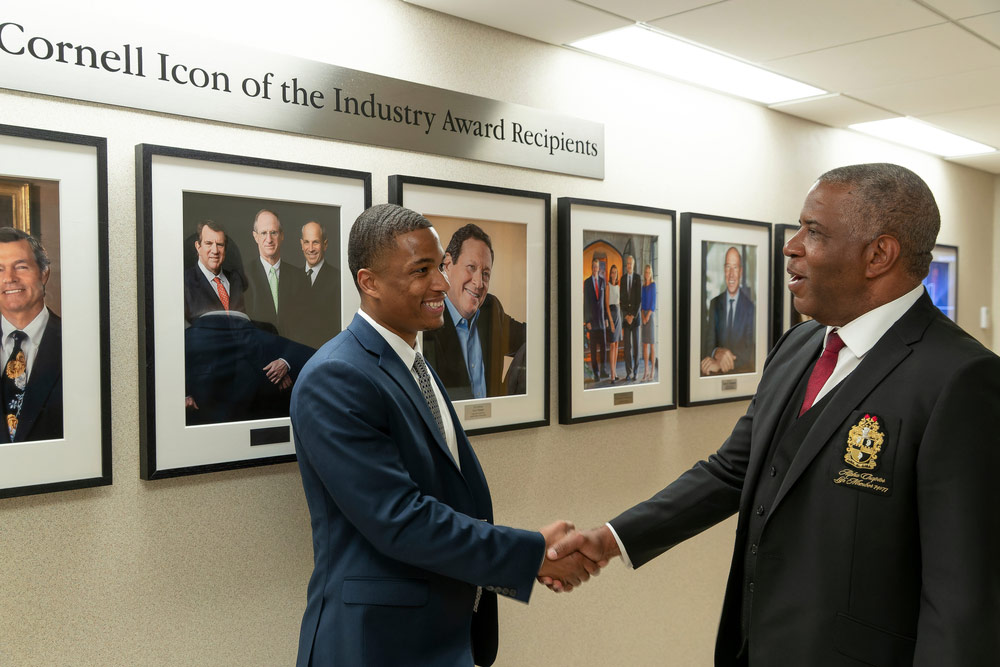 Robert F. Smith wears a suit and tie and shakes the hand of another fellow Cornell University graduate