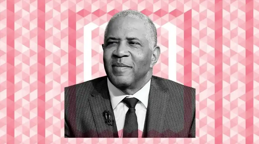 Robert F. Smith in a pinstripe suit, white collard shirt and tie on top of a red patterned background