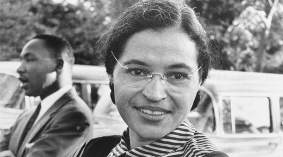 Black and white image of Rosa Parks in glasses while smiling outside.