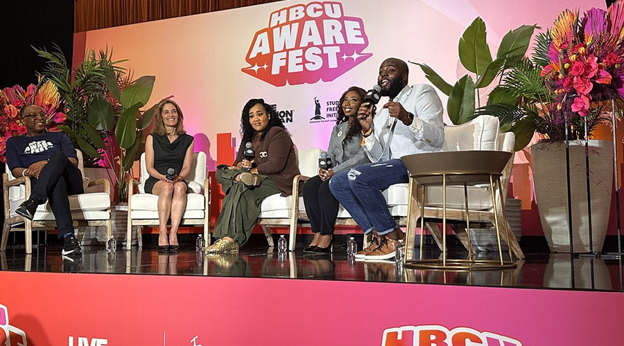 Students sitting on a stage with the HBCU AWAREFEST logo behind them.